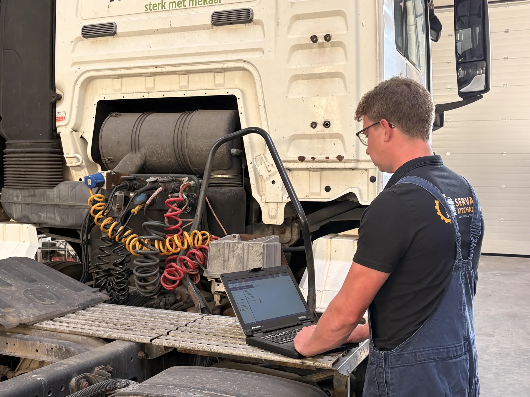 Monteur van Servaes Mechaniek leest met een laptop de foutcodes van een vrachtwagen uit