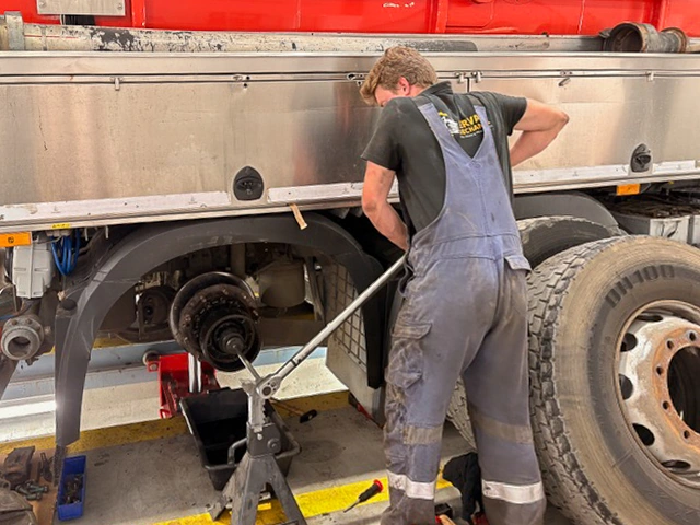 Monteur van Servaes Mechaniek werkt aan de wielnaaf van een aanhangwagen in de werkplaats